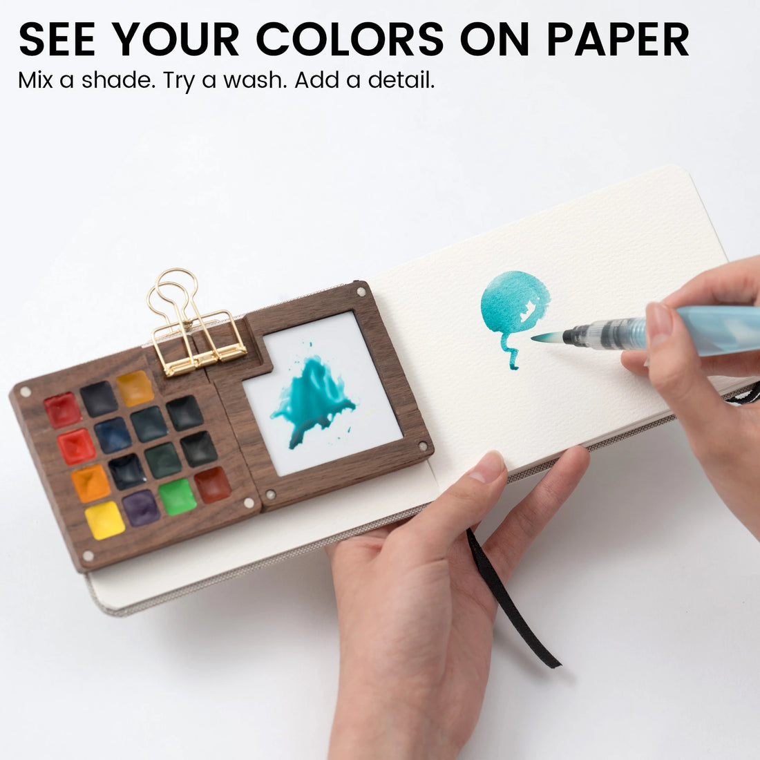 Painting a turquoise shape beside an open wooden EXPLORER watercolor palette