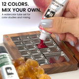 Squeezing red watercolor paint from a tube into a metal palette