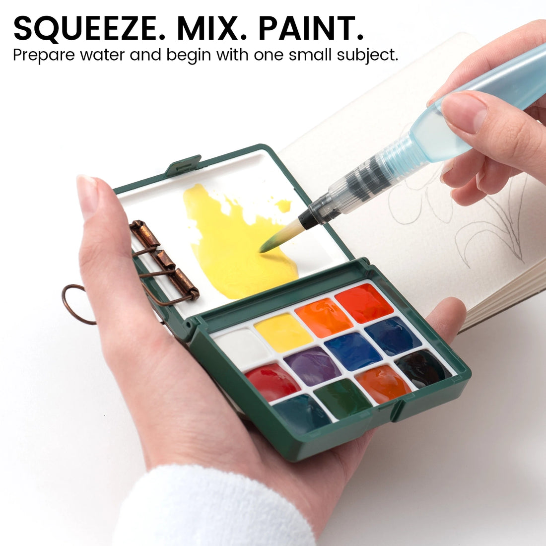 Water brush mixing yellow paint in the lid of a green portable watercolor palette