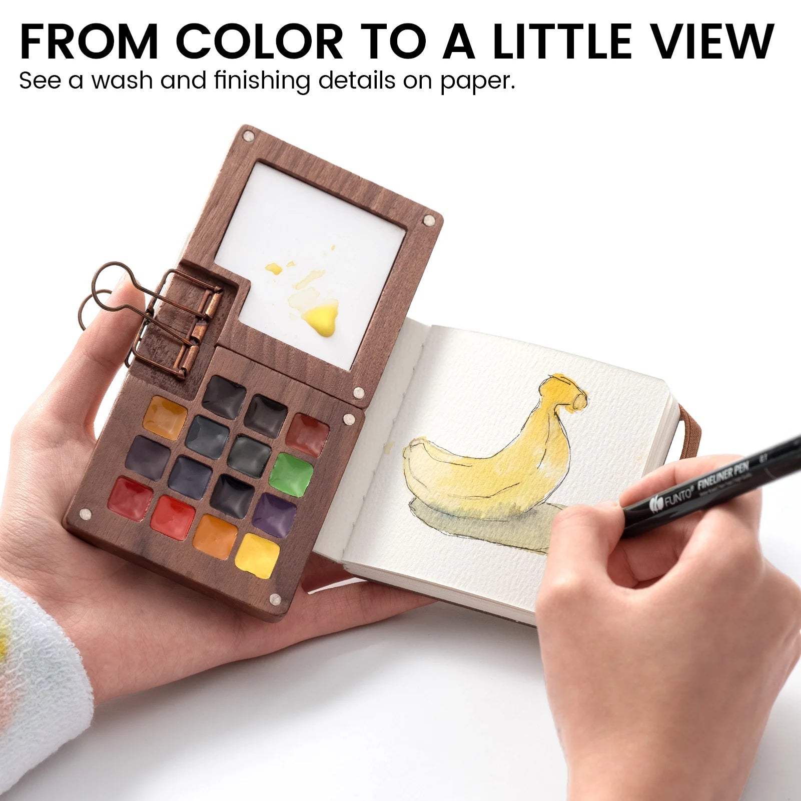 Painting a yellow duck in a small journal beside a wooden watercolor palette